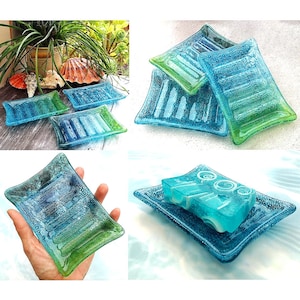 Op de afbeelding: Set van vier blauwe en groene glazen zeepbakjes. De bakjes hebben een getextureerd oppervlak en zijn perfect voor het bewaren van zeep.