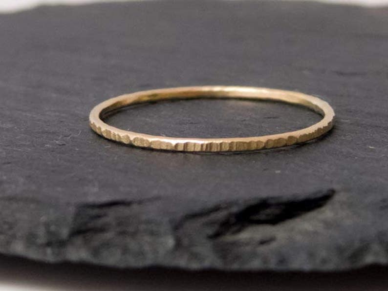 K&ouml;nnte beinhalten: Ein d&uuml;nner Goldring mit geh&auml;mmerter Textur.