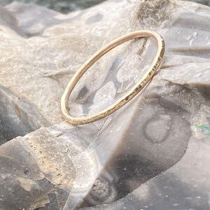 K&ouml;nnte beinhalten: Ein d&uuml;nner, geh&auml;mmerter Goldring auf einer grauen, strukturierten Oberfl&auml;che.