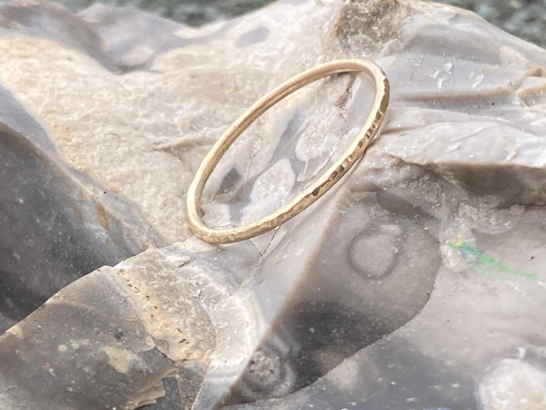 K&ouml;nnte beinhalten: Ein d&uuml;nner, geh&auml;mmerter Goldring auf einer grauen, strukturierten Oberfl&auml;che.