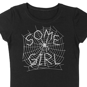 May include: Black t-shirt with a white spider web design and the text "SOME GIRL" inside the web.