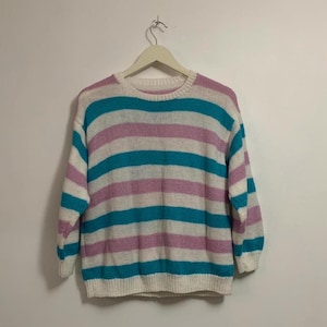 May include: A white, pink, and turquoise striped sweater with long sleeves.