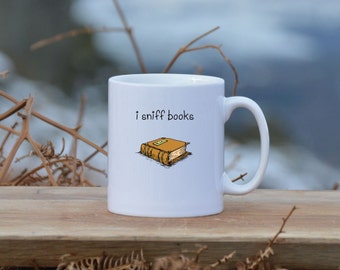 May include: White ceramic mug with a black outline of a book and the text "i sniff books" printed on it.