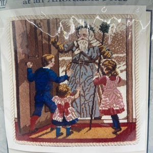 May include: Needlepoint kit featuring a scene with a figure in a long coat and children. The image has a beige border and the text "at an Affordable Price". The figures are in a room with a door and a window.