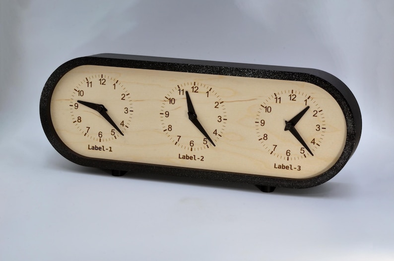 May include: A wooden clock with three separate clock faces, each with black hands and black Roman numeral markings. The clock faces are labeled "Label-1", "Label-2", and "Label-3".