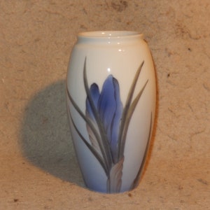 Può includere: Un vaso in ceramica bianca con un disegno di fiore di croco blu e verde. Il vaso ha un fondo arrotondato e un'apertura stretta.