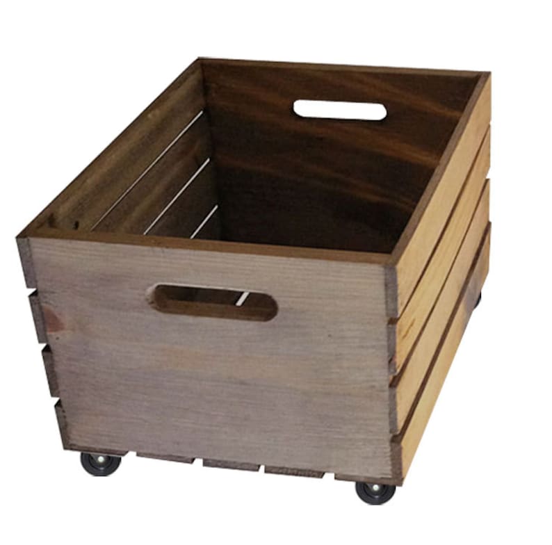 Pu&ograve; includere: Una cassa di legno con una finitura marrone invecchiata e due ruote. La cassa ha una maniglia sul davanti e sul lato.