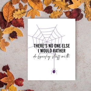 May include: A white card with a purple spiderweb design and a purple spider hanging below. The text reads "THERE'S NO ONE ELSE I WOULD RATHER do spooky stuff with."