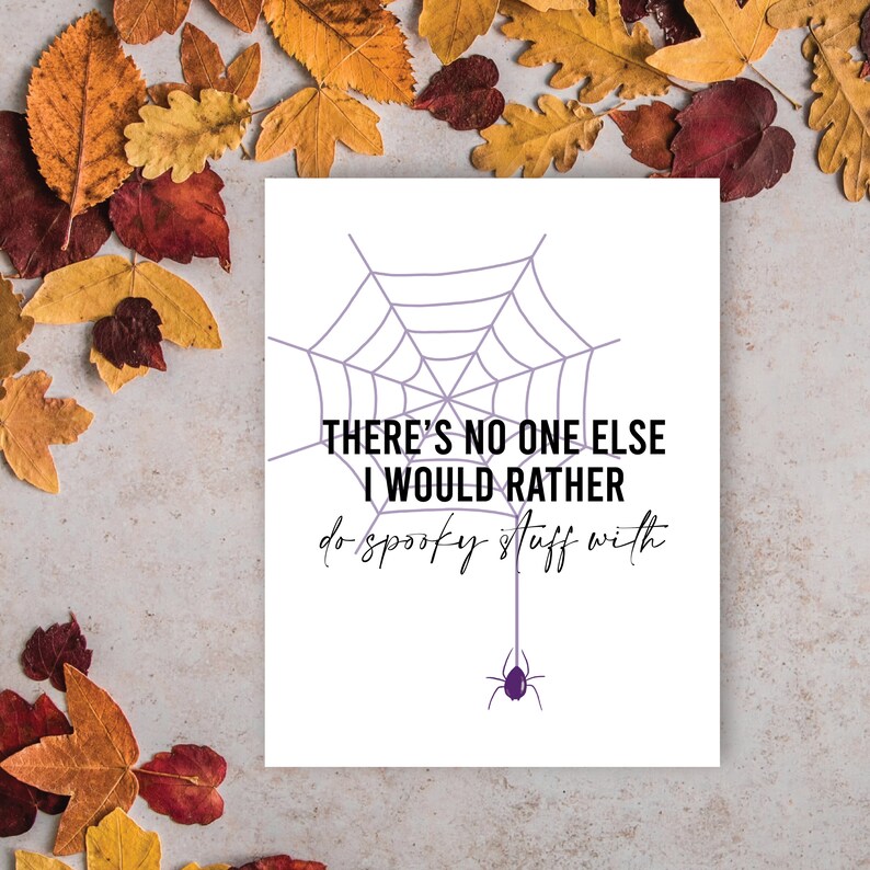 May include: A white card with a purple spiderweb design and a purple spider hanging below. The text reads "THERE'S NO ONE ELSE I WOULD RATHER do spooky stuff with."
