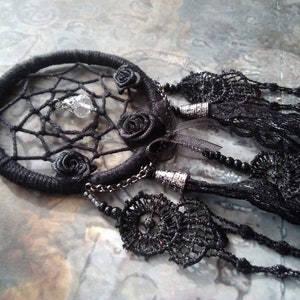 May include: Black dreamcatcher with a crystal charm and black rose embellishments. The dreamcatcher has a black lace fringe and a black beaded chain.