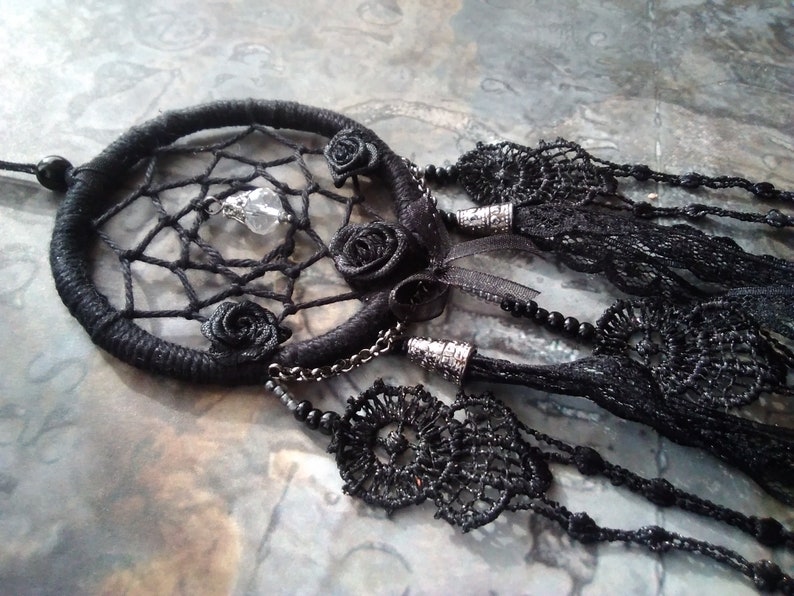 May include: Black dreamcatcher with a crystal charm and black rose embellishments. The dreamcatcher has a black lace fringe and a black beaded chain.