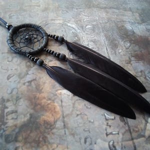 May include: A black dreamcatcher necklace with black feathers and beads. The dreamcatcher is circular and has a web-like design.