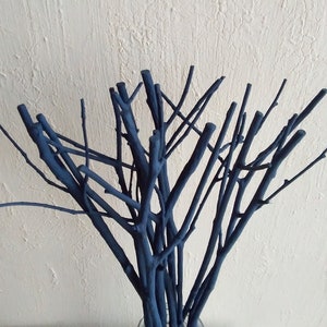 Peut inclure: Un bouquet de brindilles peintes en bleu fonc&eacute; dispos&eacute;es dans un vase. Les brindilles sont fines et ont un aspect naturel et rustique.