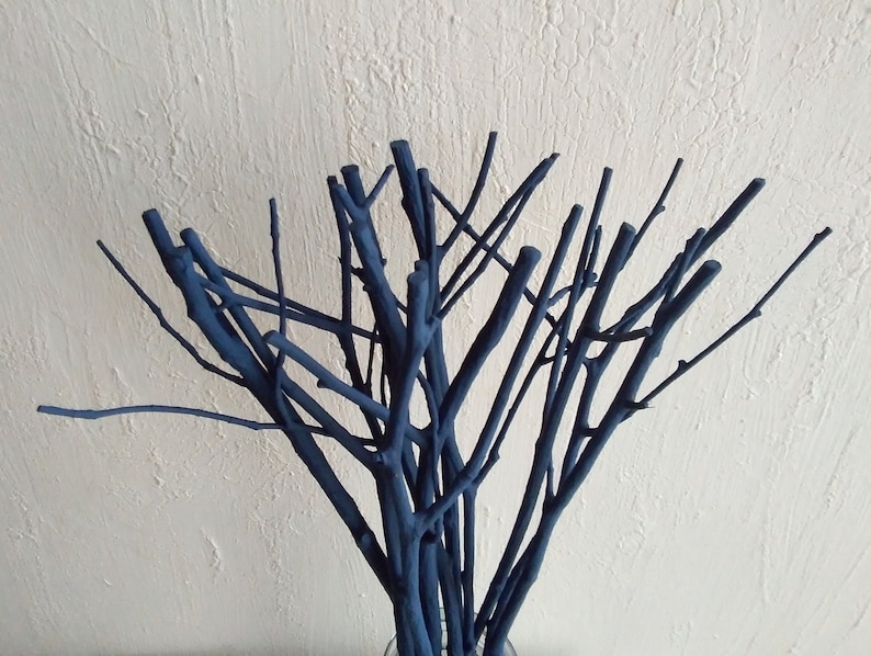 Peut inclure: Un bouquet de brindilles peintes en bleu fonc&eacute; dispos&eacute;es dans un vase. Les brindilles sont fines et ont un aspect naturel et rustique.