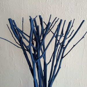 Peut inclure: Un bouquet de brindilles peintes en bleu fonc&eacute;, dispos&eacute;es en forme de vase. Les brindilles sont fines et ont un aspect naturel et rustique.