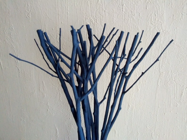 Peut inclure: Un bouquet de brindilles peintes en bleu fonc&eacute;, dispos&eacute;es en forme de vase. Les brindilles sont fines et ont un aspect naturel et rustique.