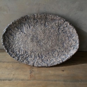 May include: A large, oval-shaped ceramic serving dish with a textured, speckled surface in shades of brown and gray.