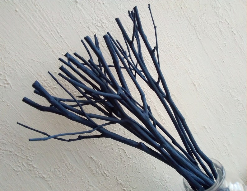 Peut inclure: Un bouquet de brindilles peintes en bleu fonc&eacute; dans un vase en verre transparent. Les brindilles sont dispos&eacute;es en &eacute;ventail.