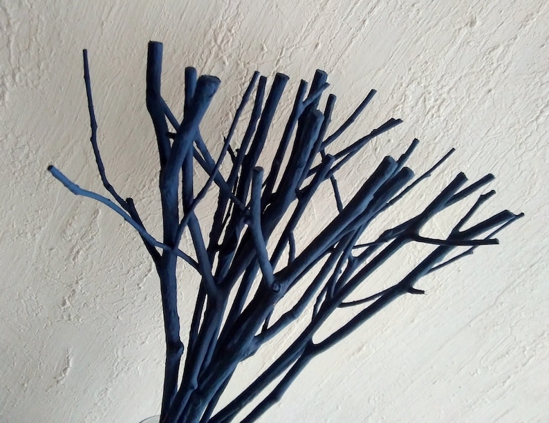 Peut inclure: Un bouquet de brindilles peintes en bleu fonc&eacute; dispos&eacute;es dans un vase. Les brindilles sont fines et ont un aspect naturel et rustique.
