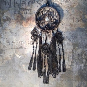 May include: Black dreamcatcher with beaded fringe and black feathers. The dreamcatcher has a crystal bead in the center and black roses around the outer edge.