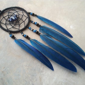 May include: A black dreamcatcher with blue feathers and a lapis lazuli stone in the center.