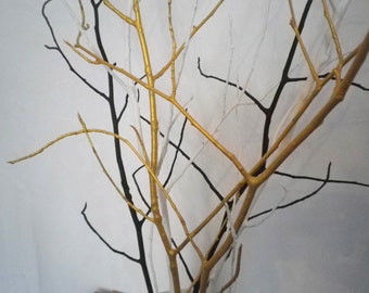 May include: A set of branches painted in gold and white, creating a decorative display. The branches are arranged in a criss-cross pattern, with the gold branches on top of the white branches.