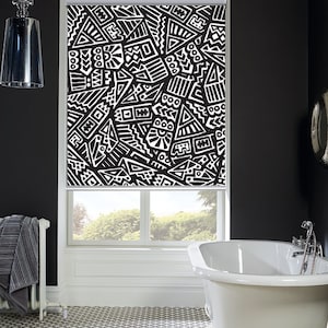 May include: Black and white geometric patterned roller blind in a bathroom with a white bathtub and a black and white tiled floor.