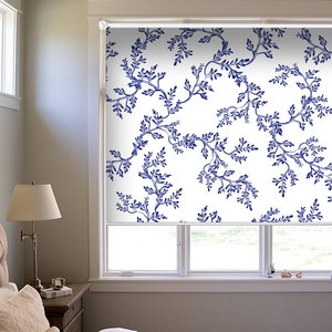 May include: White window shade with a blue floral pattern. The shade is pulled down halfway, revealing a window with two panes.
