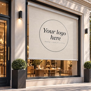 May include: A beige roller blind installed on a storefront window, featuring a black circular graphic with the text Your logo here and the words BRAND QUALITY STYLE underneath. The blind is mounted in a modern frame with two black wall lamps.