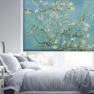 May include: A white bed with a gray and white striped duvet cover and a gray throw blanket. The window behind the bed has a white roller shade with a printed image of a blue sky and a white flowering tree branch.