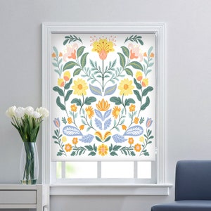May include: White window blind with a floral design featuring yellow, orange, blue, and green flowers. The flowers are arranged in a symmetrical pattern.