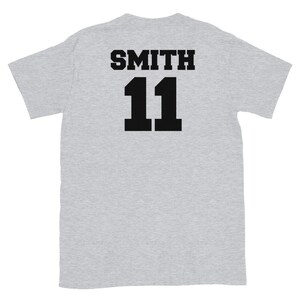 K&ouml;nnte beinhalten: Graues T-Shirt mit schwarzem Text auf der R&uuml;ckseite, der "SMITH 11" lautet.
