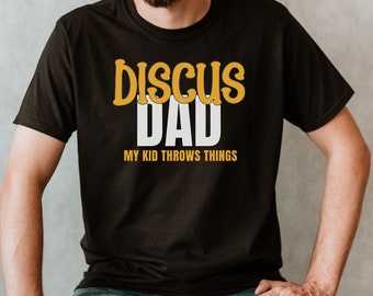 May include: Black t-shirt with the text "Discus Dad" in yellow and white. The text "My Kid Throws Things" is printed in white below the main text.