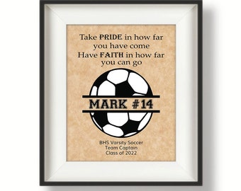 May include: A framed motivational print with a soccer ball graphic and the text "Take PRIDE in how far you have come Have FAITH in how far you can go MARK #14 BHS Varsity Soccer Team Captain Class of 2022".