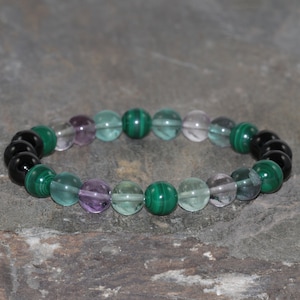 Peut inclure: Un bracelet en perles avec des pierres noires, vertes et violettes.