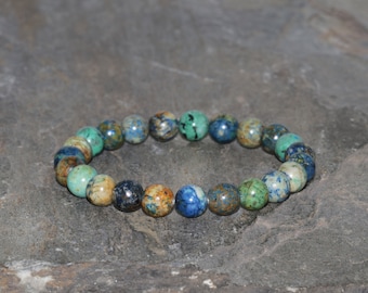 May include: A bracelet made of blue, green, and brown gemstone beads. The beads are round and have a natural, rough texture.