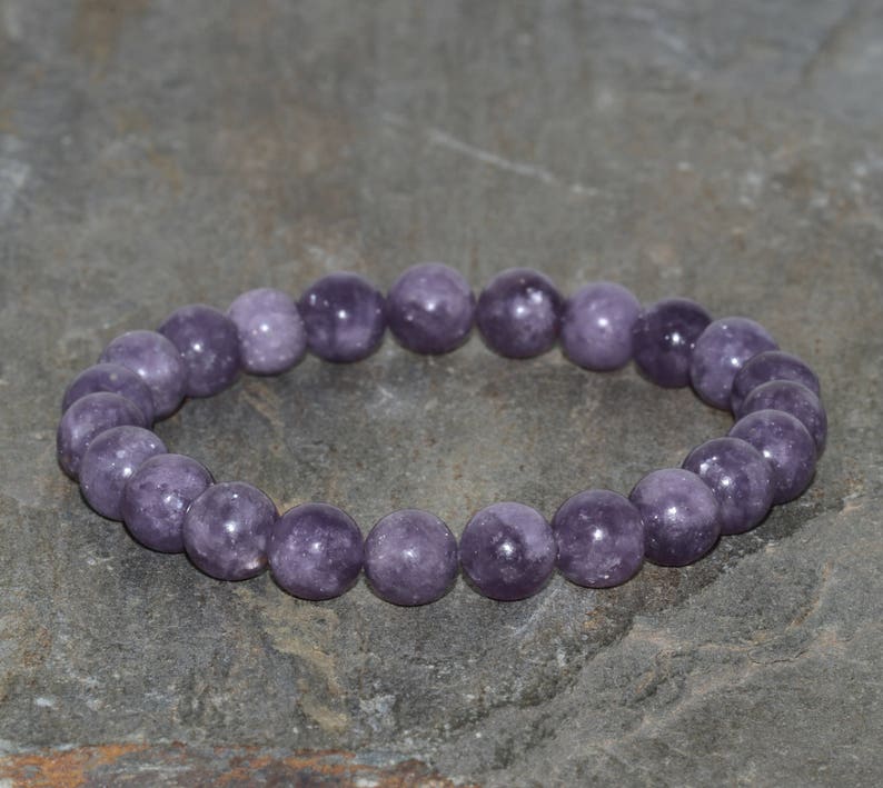 May include: A purple gemstone bracelet with round beads. The bracelet is made of natural stones and is approximately 8 inches in length.