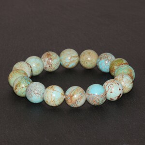 May include: A turquoise and brown gemstone bracelet with round beads. The bracelet is made of natural stones and has a unique, marbled pattern.