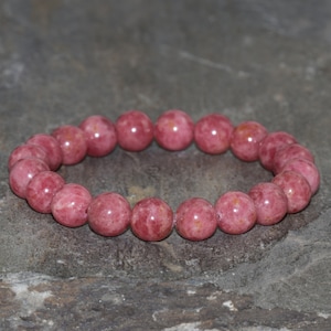 May include: A pink gemstone bracelet with round beads. The bracelet is made of natural stones and is a beautiful accessory for any occasion.