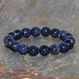 Puede incluir: Un brazalete de piedras azules redondas. El brazalete está hecho de piedras naturales y es un hermoso accesorio para cualquier ocasión.