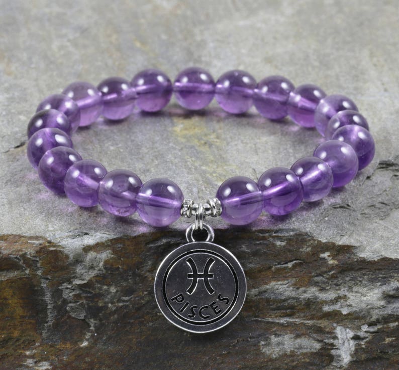 Puede incluir: Pulsera de piedras preciosas de amatista p&uacute;rpura con un dije de plata que dice "Piscis".