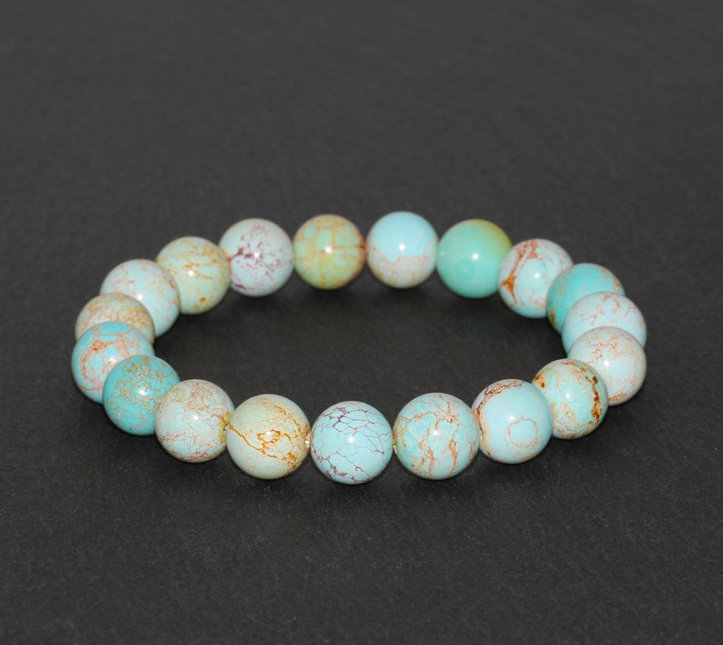 May include: A turquoise and brown beaded bracelet with a round shape. The beads are made of a natural stone with a marbled pattern.