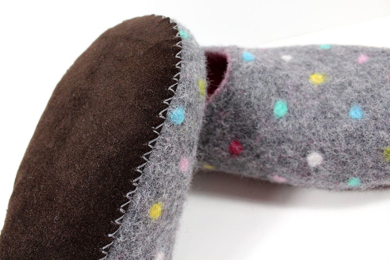 May include: A pair of gray felt slippers with colorful polka dots. The slippers have a brown suede sole and a zig-zag stitch around the edge.