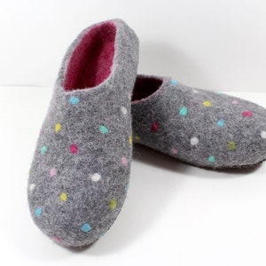 May include: A pair of gray felt slippers with a colorful polka dot pattern. The slippers have a pink lining and a closed toe.
