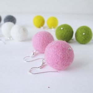 Peut inclure: Une paire de boucles d'oreilles pendantes avec des boules de feutre rose et vertes. Les boucles d'oreilles ont des crochets argentés.