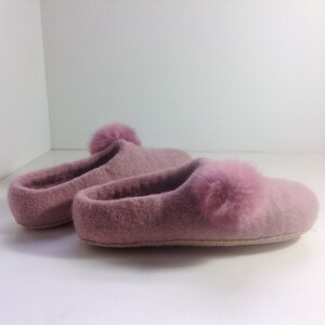 Può includere: Coppia di pantofole rosa pelose con un pon pon sulla parte superiore di ogni pantofola.