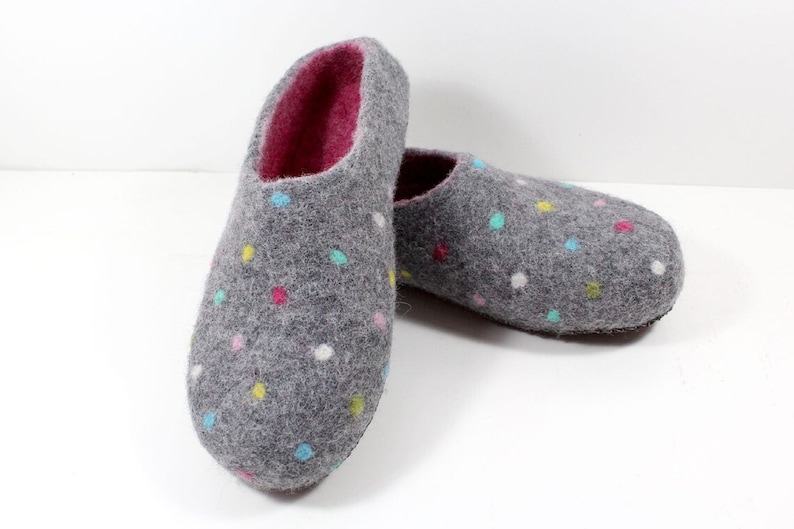 May include: A pair of gray felt slippers with a colorful polka dot pattern. The slippers have a pink lining and a closed toe.