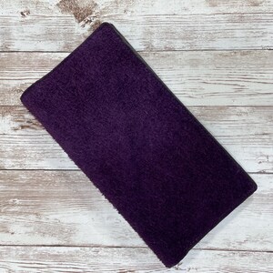 May include: A purple suede wallet with a dark gray border.