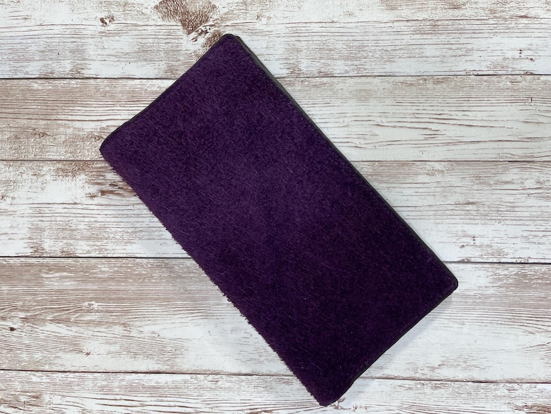 May include: A purple suede wallet with a dark gray border.