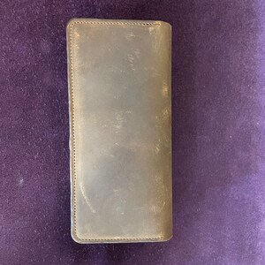 May include: A brown leather wallet with a stitched edge.